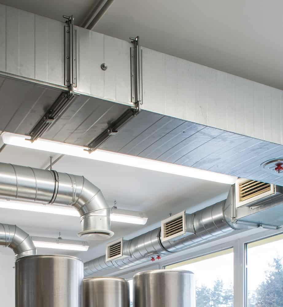 A ventilation system showing multiple pipes, vents, and air exchangers above a commercial kitchen.
