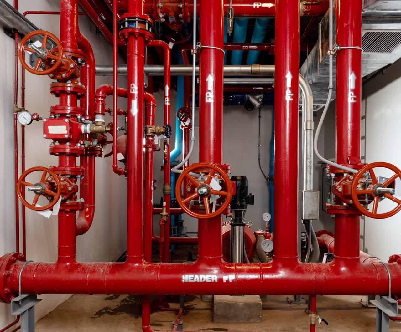 Fire system standpipes and valves in the basement of a large facility.